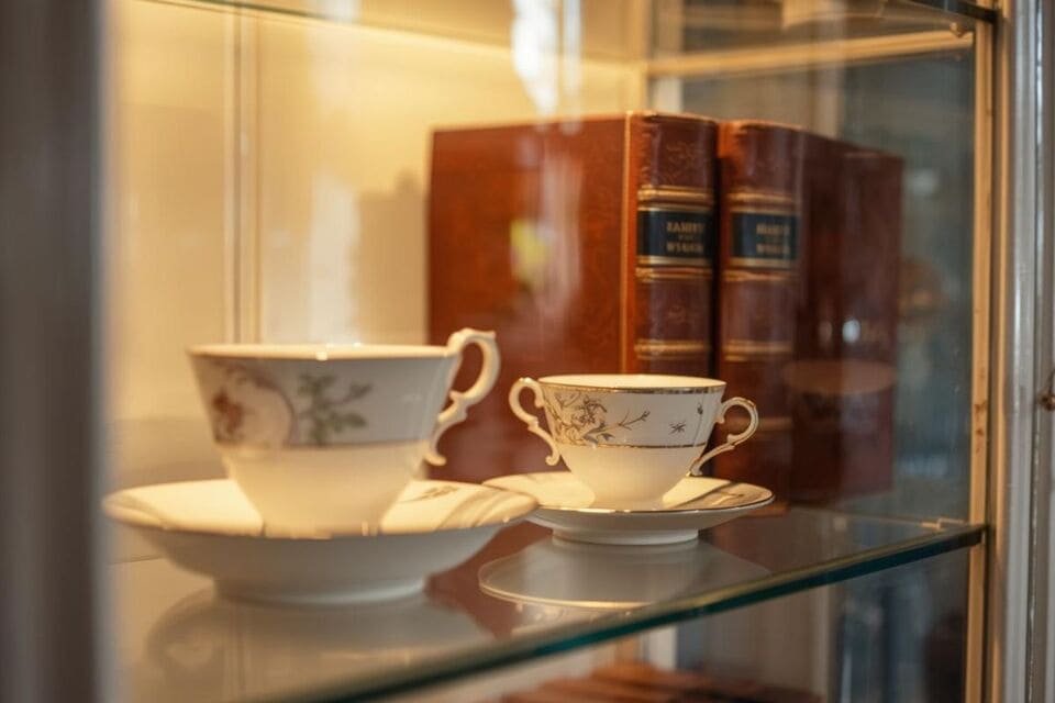 ガラス棚に飾られたティーカップや洋書